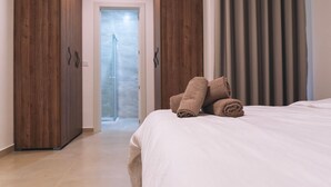 Habitación de hotel con cama, armario de madera y baño con ducha.