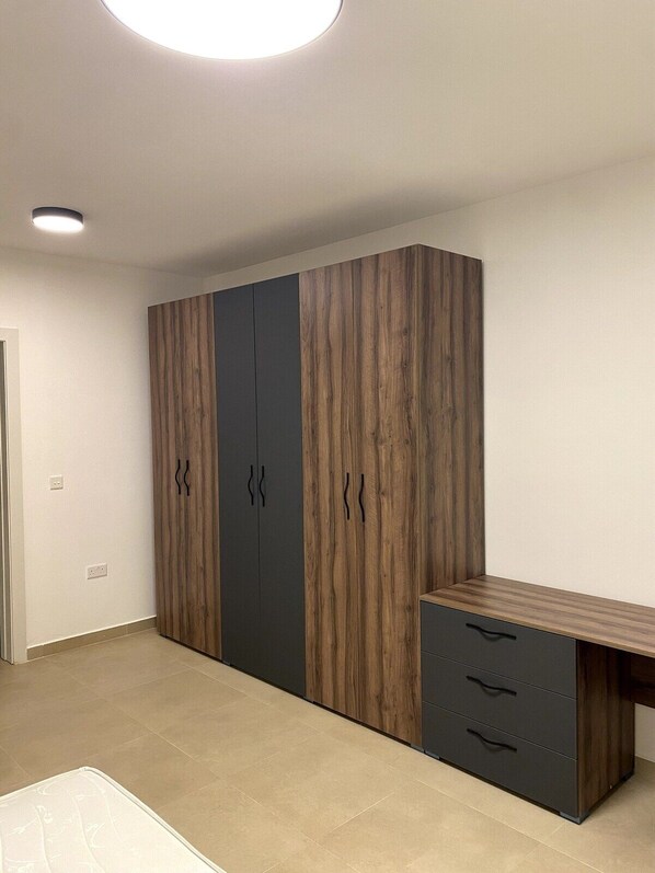 A bedroom with a bed, a wardrobe, and a desk.