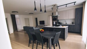 Une cuisine moderne avec un îlot central, une table à manger en bois foncé et des chaises.