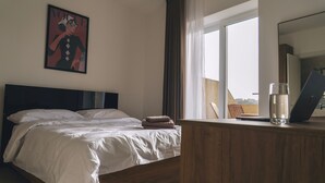 Une chambre d’hôtel avec un lit, un bureau en bois, un ordinateur portable et une fenêtre avec des rideaux.