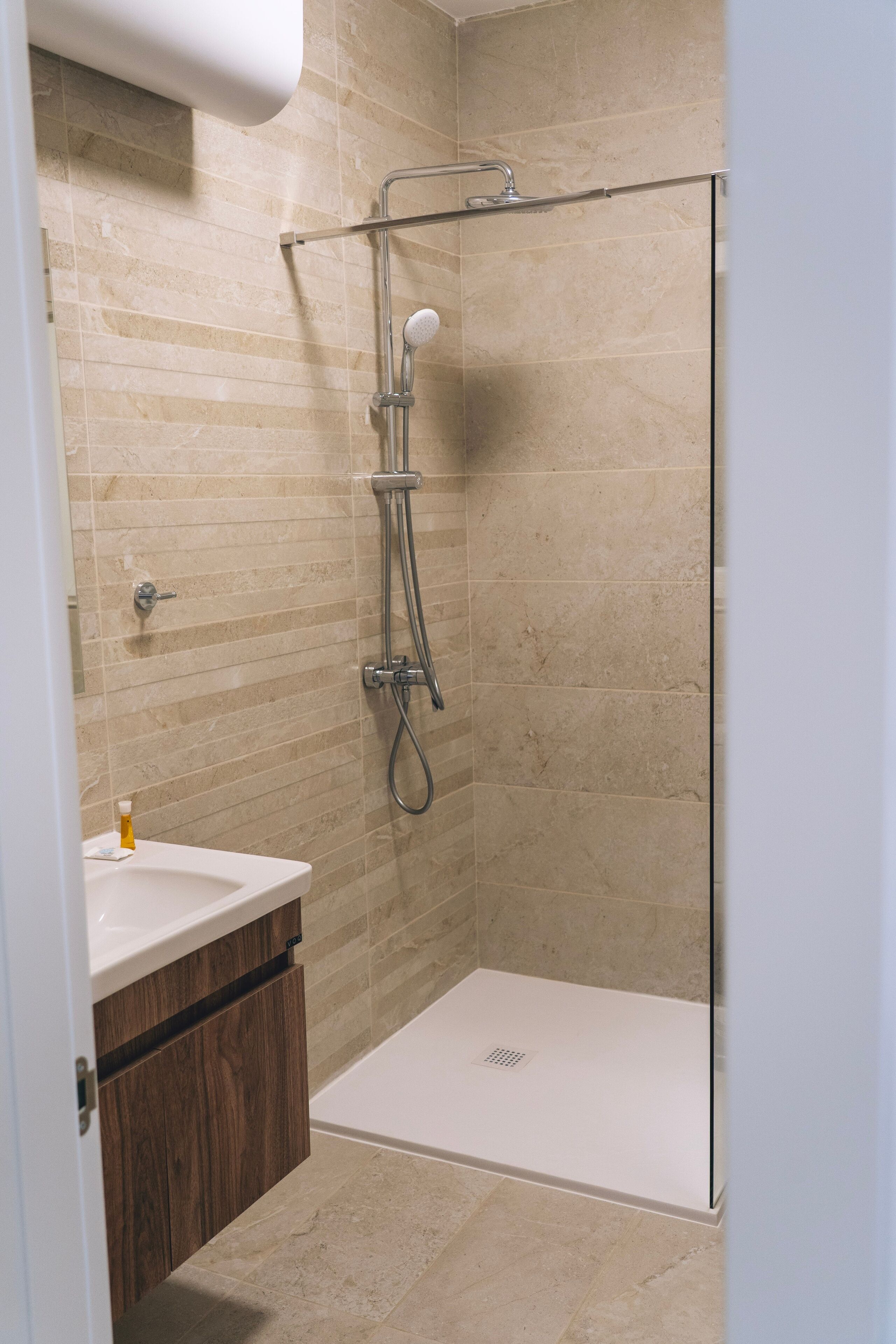 Une salle de bain avec une douche, un lavabo et des meubles en bois.