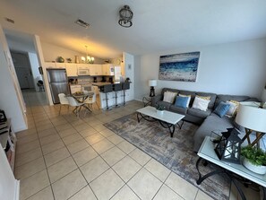 A modern living room with a grey sofa, a coffee table, and a dining area with a white table and chairs. - 4 Bedroom, 3 Bath Hampton Lakes Home With Private Pool - Near Disney! (Davenport)