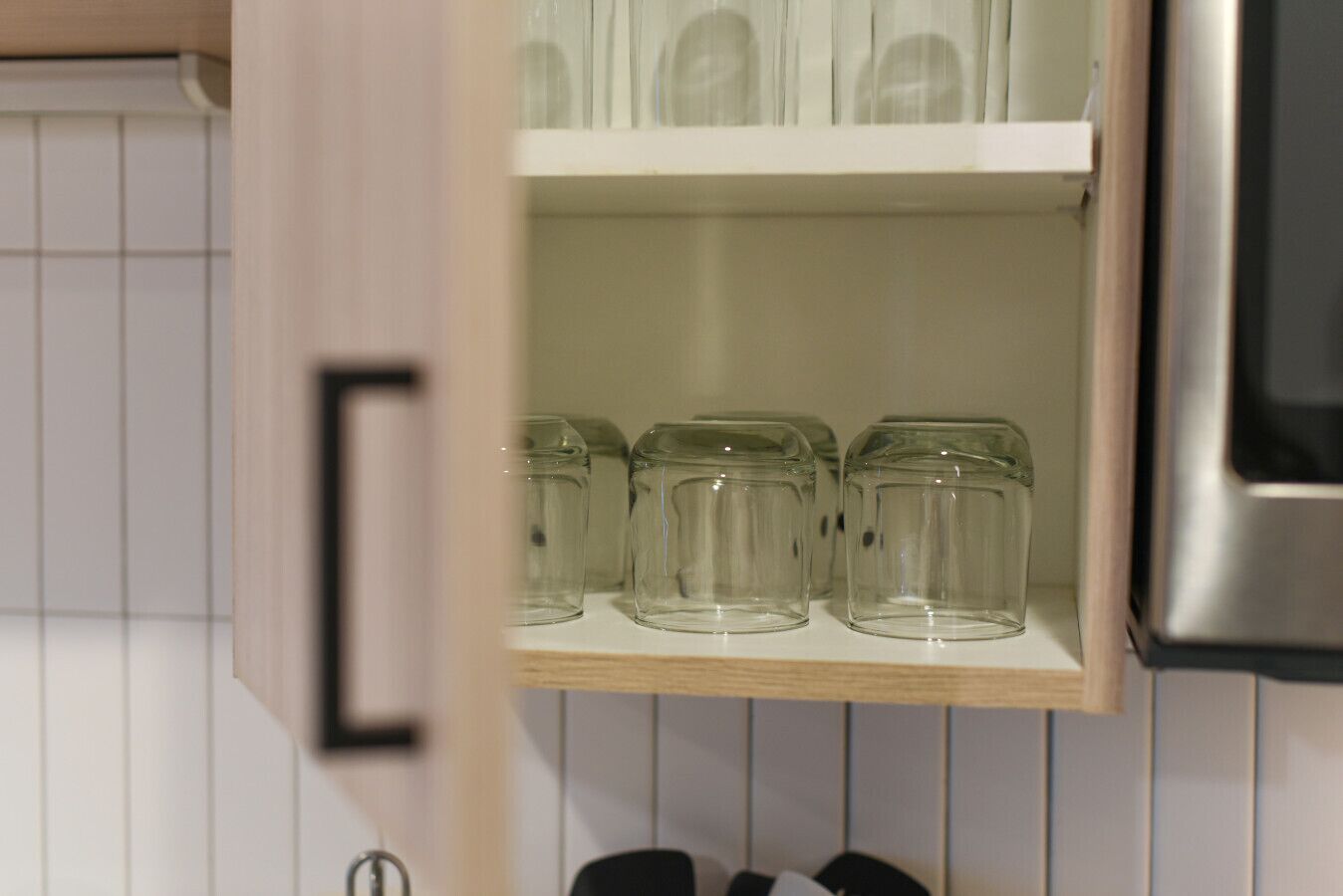A kitchen with a wooden shelf holding three clear glass jars.