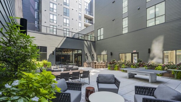 Un espace extérieur aménagé avec un patio, des sièges, une table de ping-pong et un barbecue.