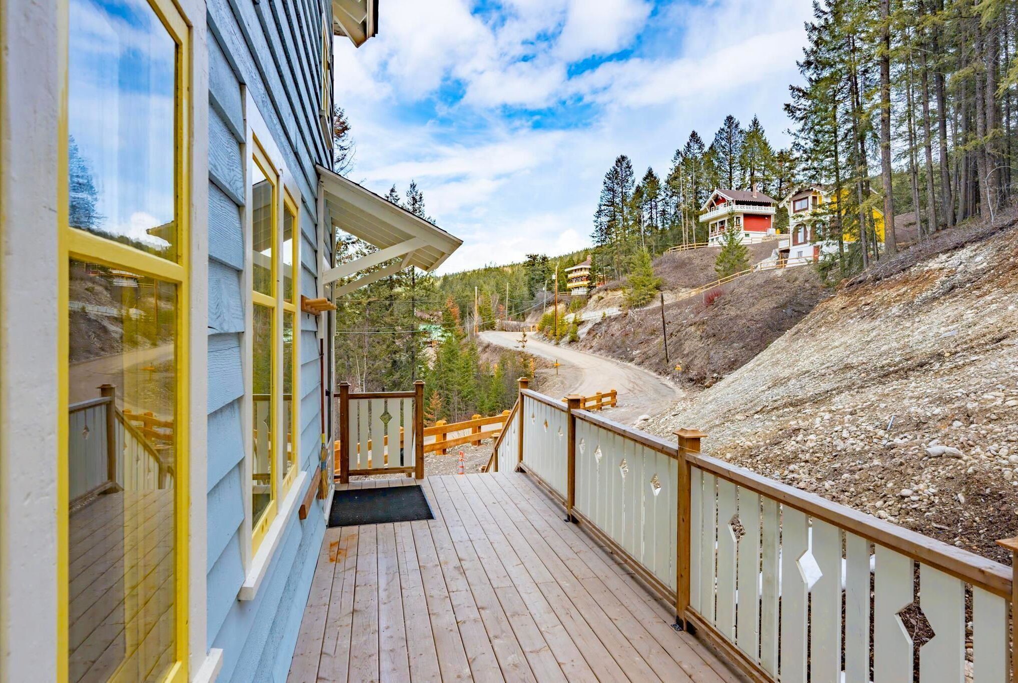 A wooden deck with a view of a forested hillside and a distant house.