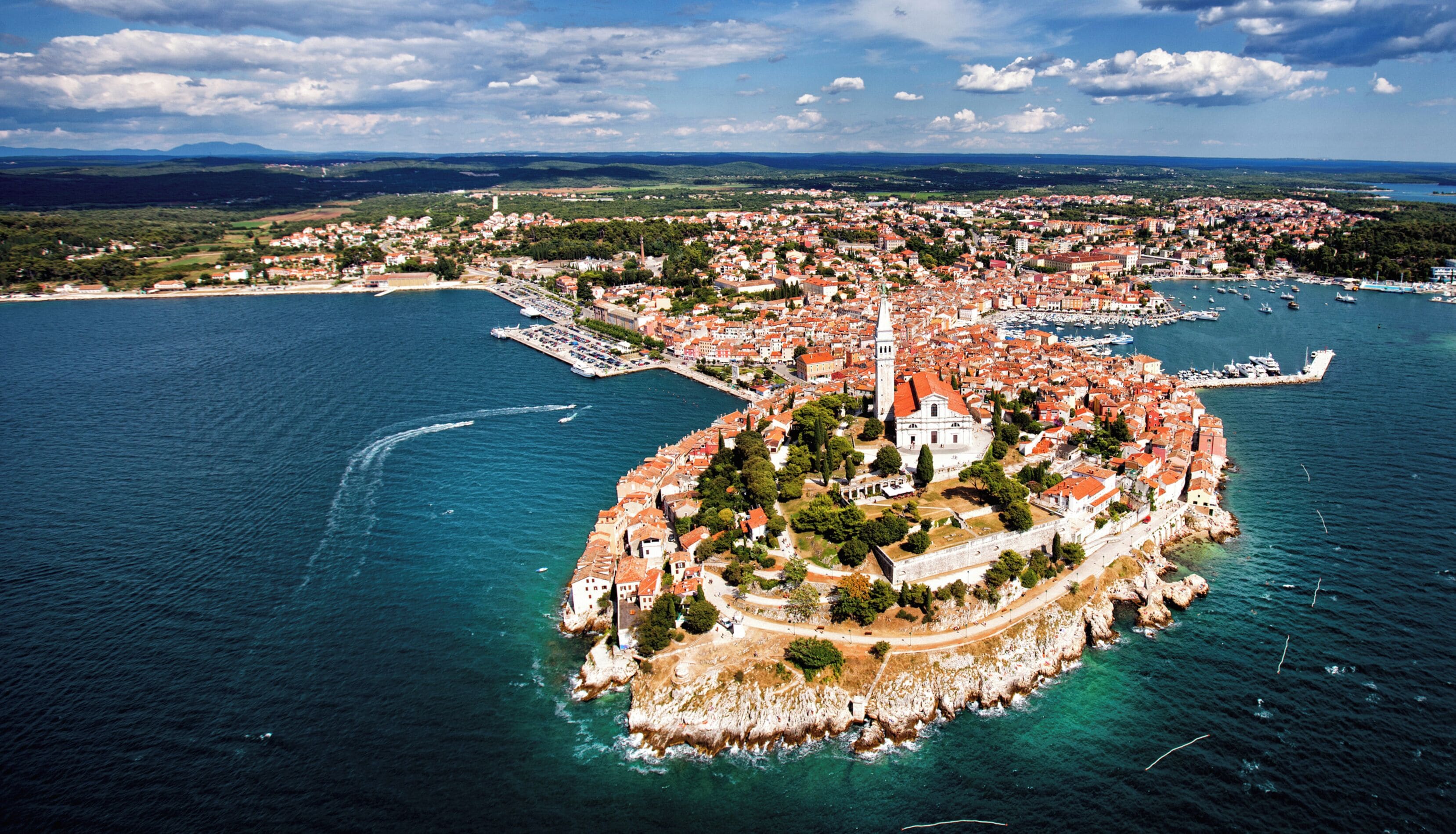 An aerial view of a coastal town with a prominent fortress-like structure surrounded by water.