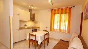Una cocina compacta con armarios blancos, una mesa de comedor con sillas y un sofá.