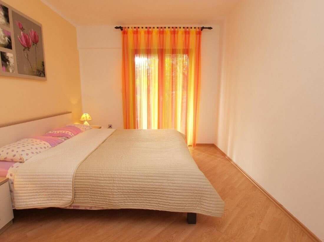 A bedroom with a bed, a nightstand, a lamp, and a window with curtains.
