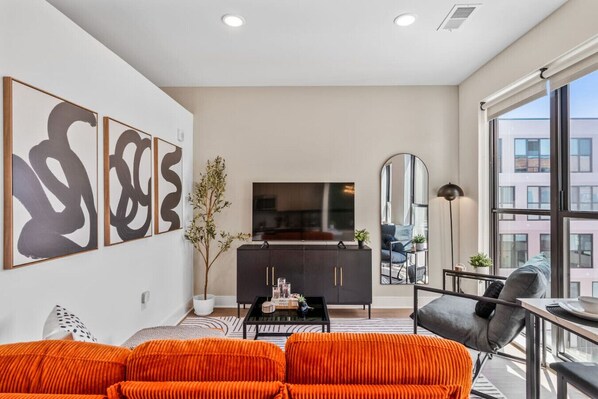 A modern living room with a sofa, a coffee table, and artwork on the wall. - OTR | King Bed l Free Parking | Gym | Top Floor (Cincinnati)