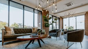 A modern living room with a sofa, armchairs, a coffee table, and large windows offering a city view.