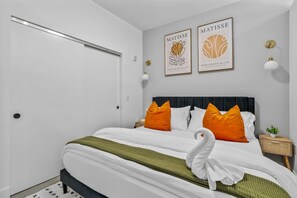 A neatly arranged bedroom with a bed, pillows, a bedside table, and two framed artworks on the wall. - OTR | King Bed l Free Parking | Gym | Top Floor (Cincinnati)