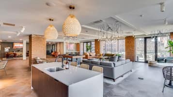 Uma cozinha moderna com uma ilha central, uma sala de jantar com uma mesa comprida e uma sala de estar com sofás e mesa de centro.