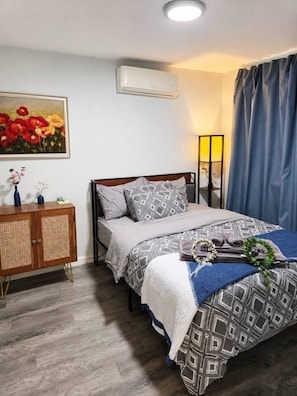 A bedroom with a bed, a bedside table, a lamp, and a painting on the wall.