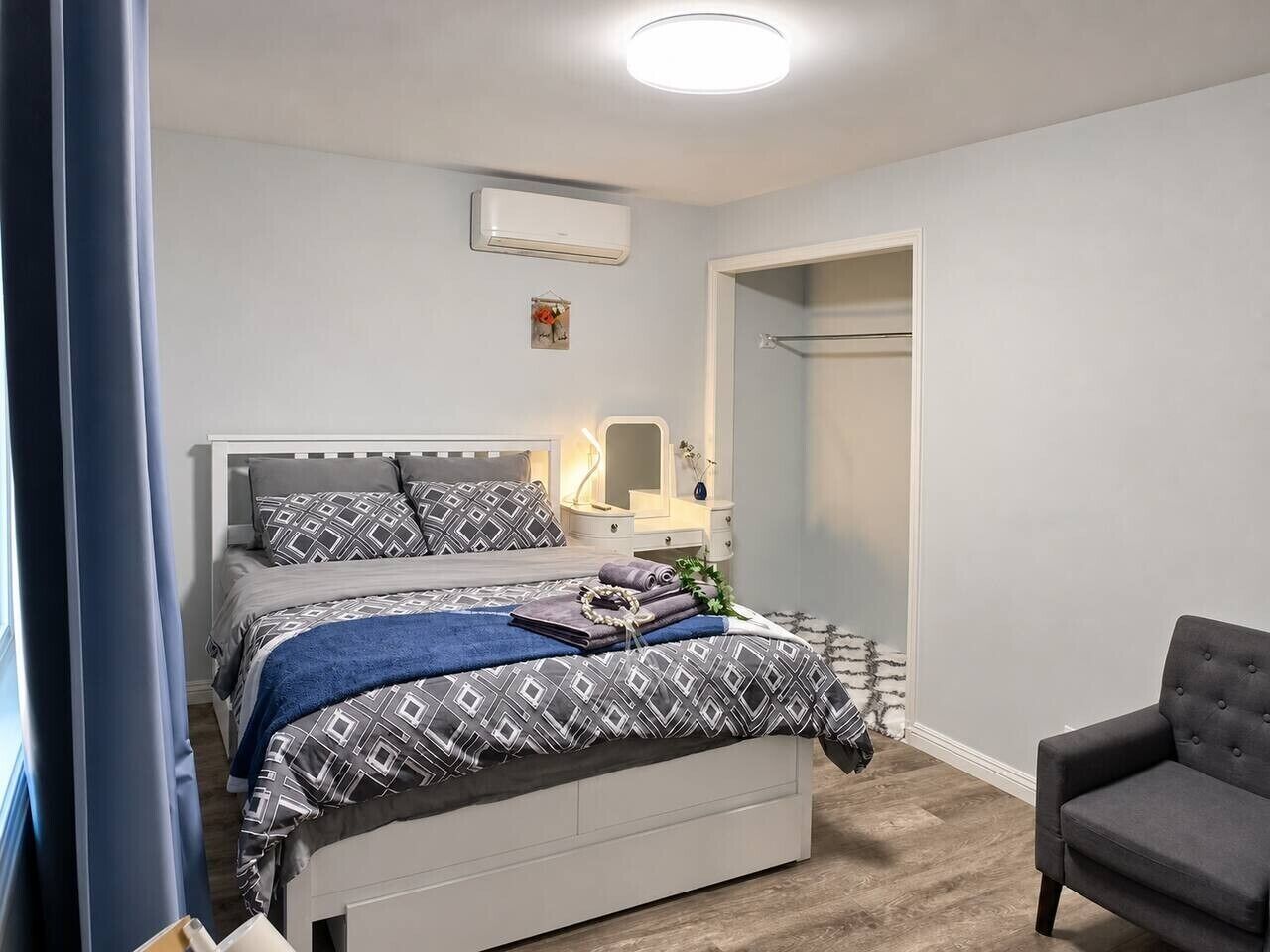 A bedroom with a bed, bedside table, and a chair.