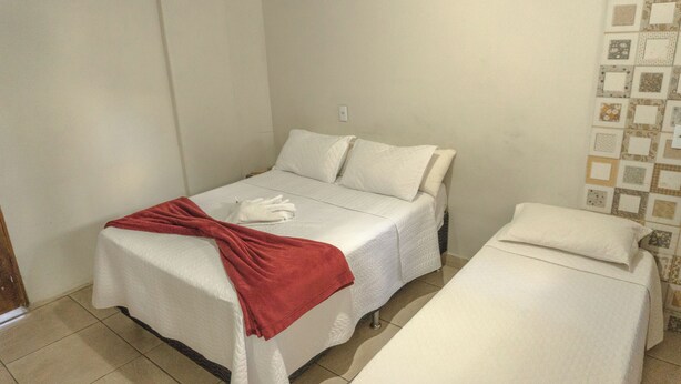 A small, clean room with a single bed and a smaller bed, both with white linens. - Comfort Suite 203 (Centro Diamantina)