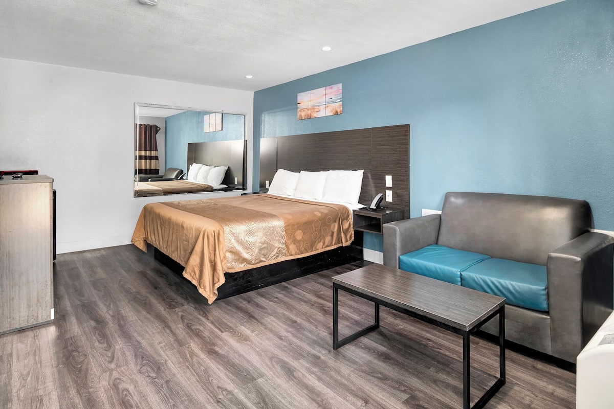 Ett modernt hotellrum med en säng, en soffa, ett soffbord och ett skrivbord.