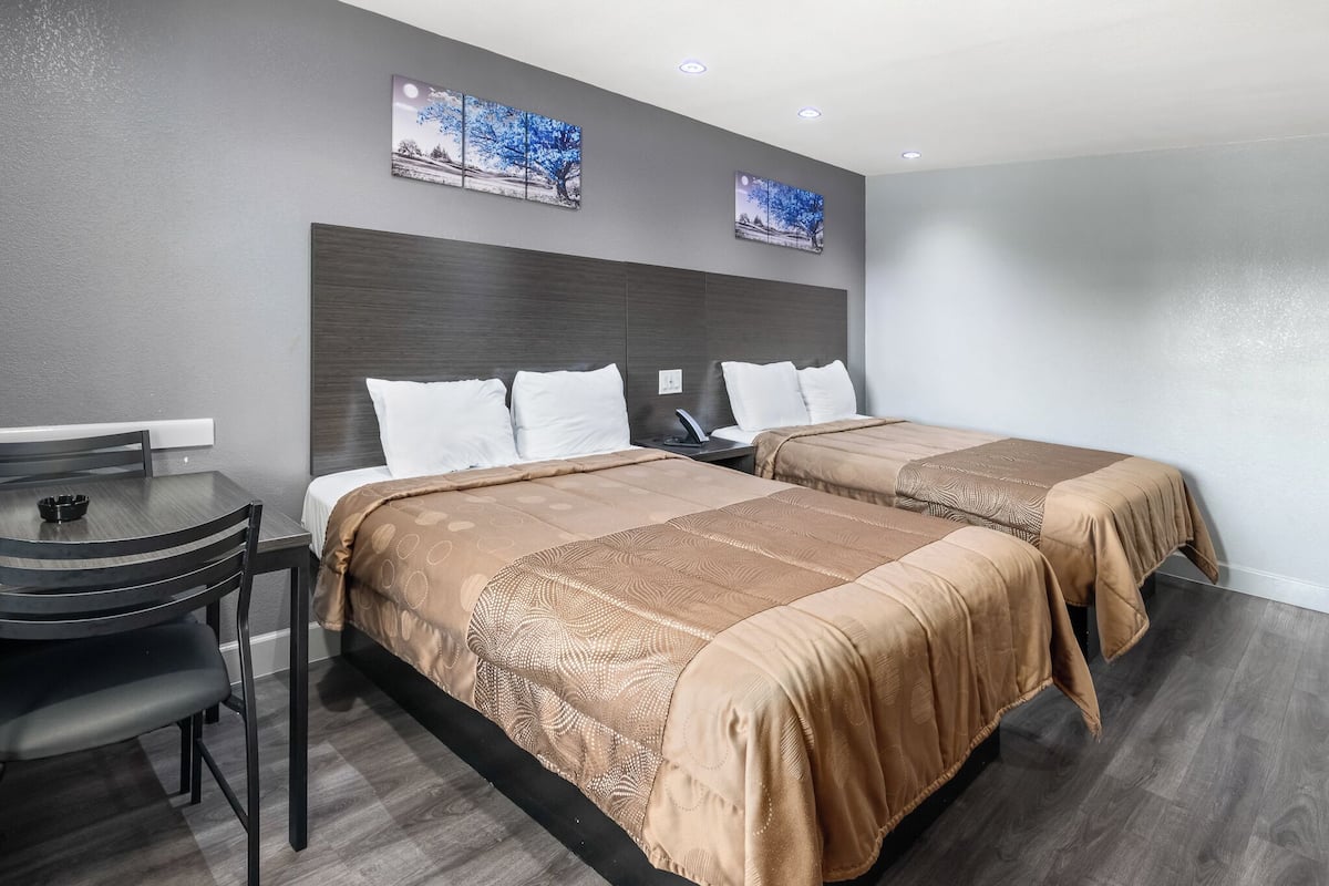 Ett hotellrum med två sängar, ett skrivbord och en stol.