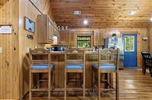 Ein Interieur einer Holzhütte mit einer Küchenzeile, Barhocker und einer blauen Tür.