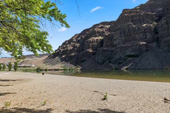 A natural landscape with a river, rocky cliffs, and sparse vegetation.