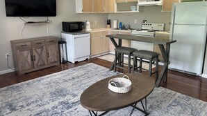 Una cocina compacta con comedor, un televisor de pantalla plana sobre la encimera y un refrigerador pequeño.