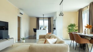 Una sala moderna con sofá, televisor y comedor.