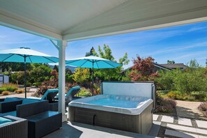 A hot tub with a patio area, outdoor furniture, and umbrellas. - Luxe, Pool, Spa, Fire Pit, Game Room, Piano Sonoma Pool Retreat by Avantstay (Kenwood)