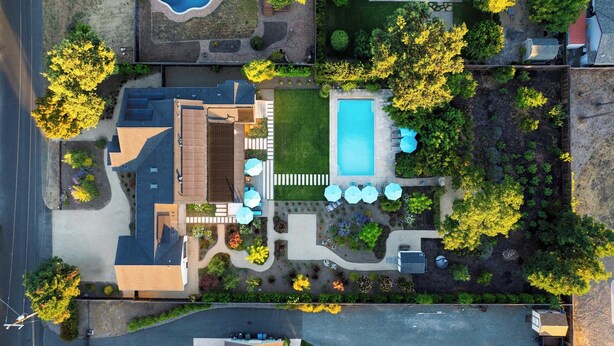 A residential property with a swimming pool, patio with umbrellas, and landscaped gardens.