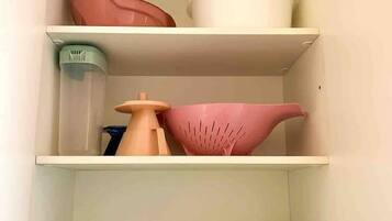 A kitchen cabinet with three shelves, containing various kitchenware items.