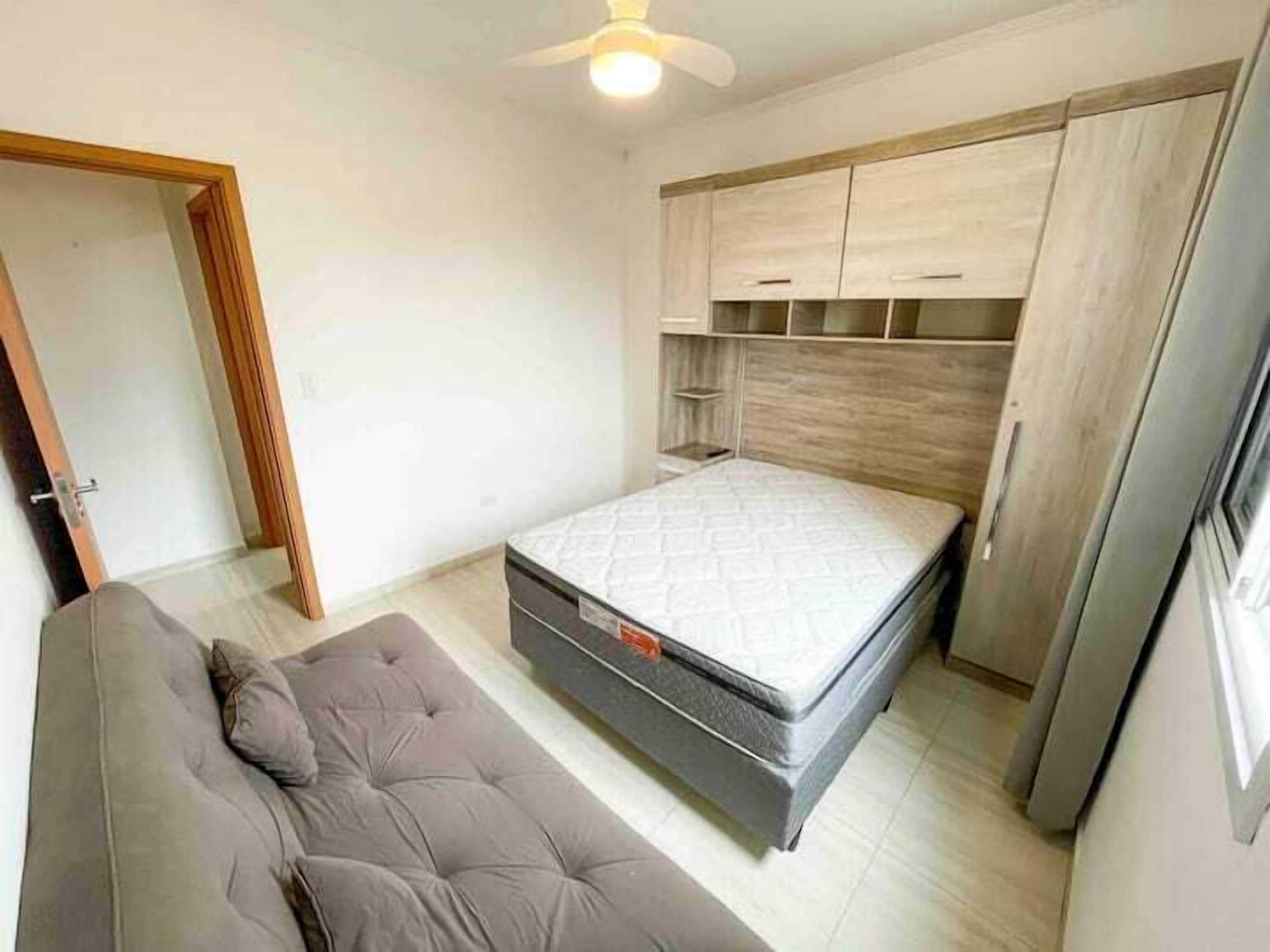 Una camera da letto con un letto, un divano grigio e un armadio.