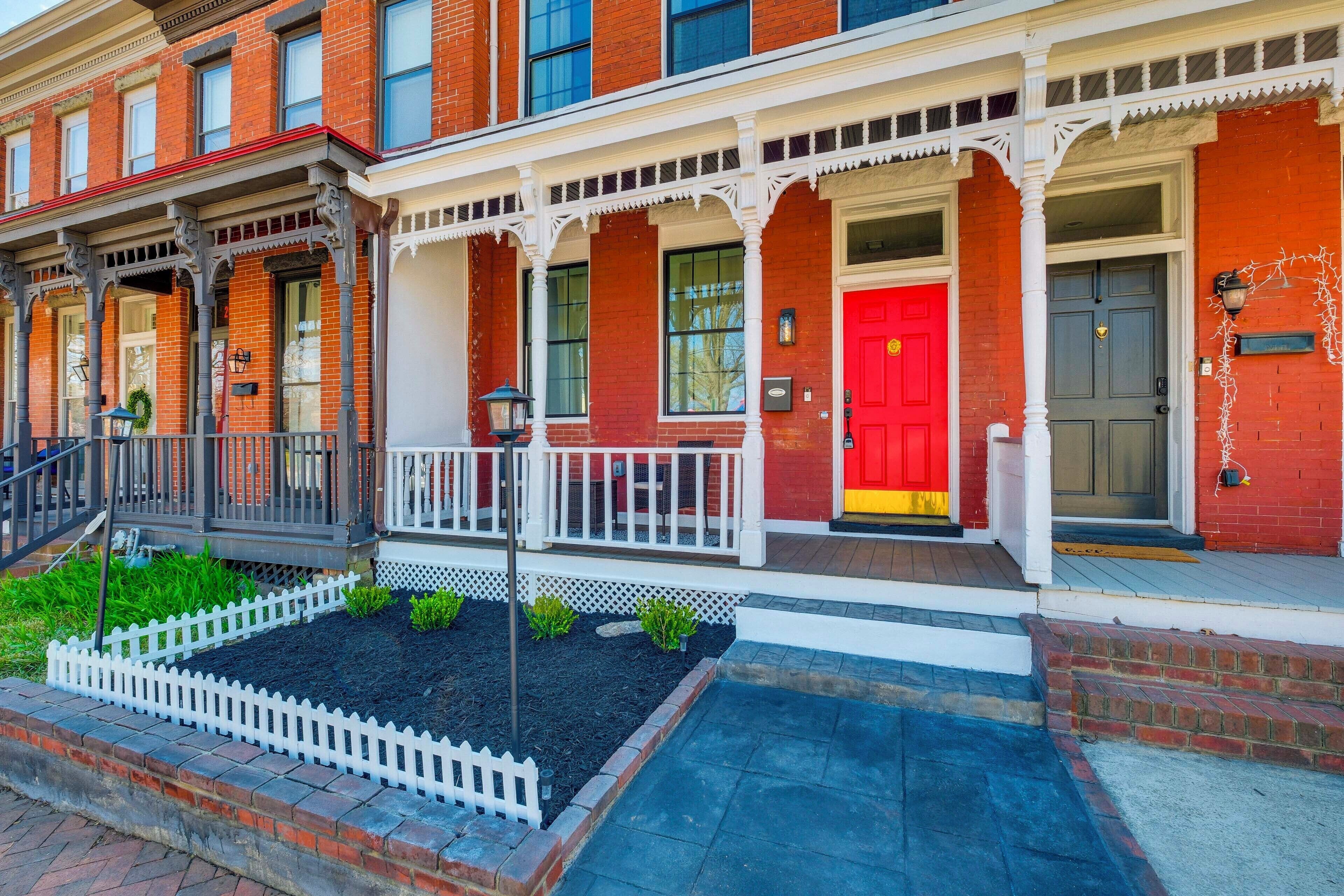 A red brick building with a white porch and a red door.