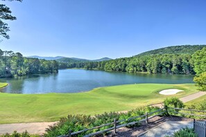 Un parcours de golf avec un lac, entouré de collines boisées.