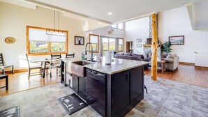 A spacious kitchen with a central island, a dining area with chairs, and a living room with a sofa and a coffee table. - Mountain-View Deck: Group Getaway in Fleetwood (Fleetwood)