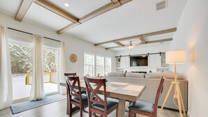 A modern living room with a wooden dining table, dark wooden chairs, a sofa, and a floor lamp. - Walk to Beach: Modern Retreat in Presque Isle! (Presque Isle)