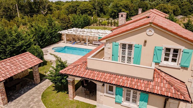 Una casa de dos pisos con piscina, mobiliario exterior y jardín.