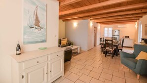 Amplia sala de estar con techo de madera, una mesa de comedor y una cocina equipada con refrigerador y microondas.