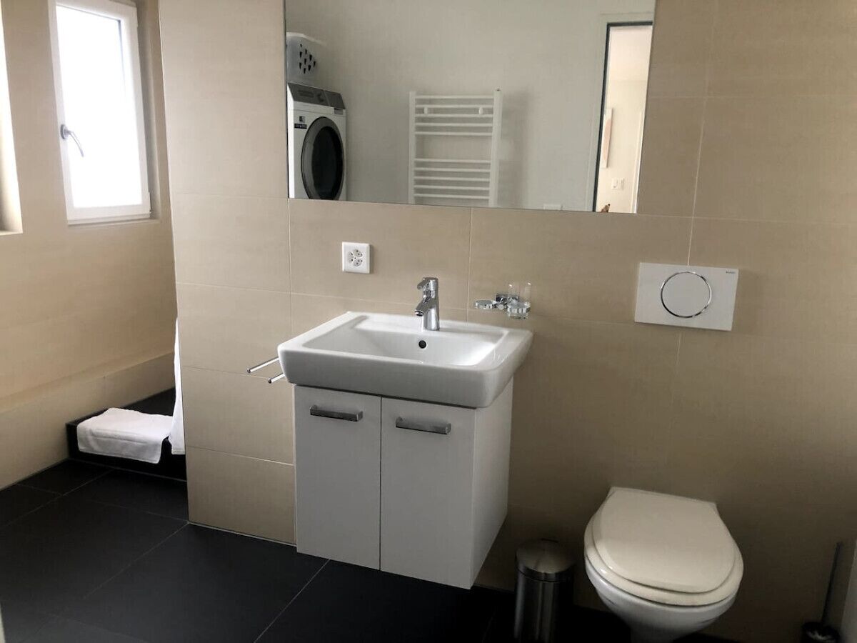 Une salle de bain moderne avec un lavabo blanc, des toilettes et un miroir.