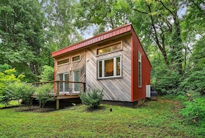 A cabin with a wooden exterior, a deck, and a small garden area.