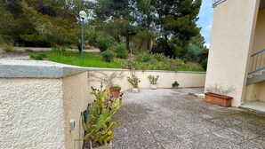 A courtyard with a gravel floor, potted cacti, and a building with a textured wall. - Apartment Blue Sea with sea view (Talamone)