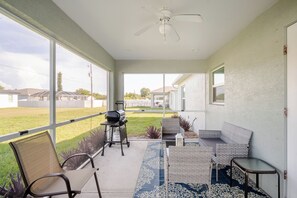 Ein überdachter Patio-Bereich mit Deckenventilator, Sitzgelegenheiten im Freien und Blick auf die Umgebung.
