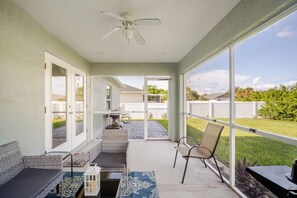 A covered patio area with a ceiling fan, outdoor seating, and a view of the backyard.