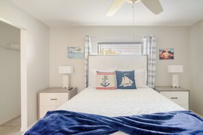 A bedroom with a bed, two bedside tables, a ceiling fan, and artwork on the walls.