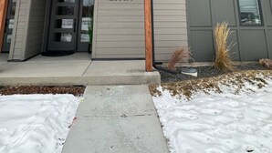 A modern building with a grey facade, a wooden entrance canopy, and a large number '2140A' displayed on the wall.