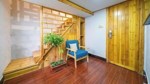 Une pièce avec un escalier en bois, une chaise bleue et une porte en bois.