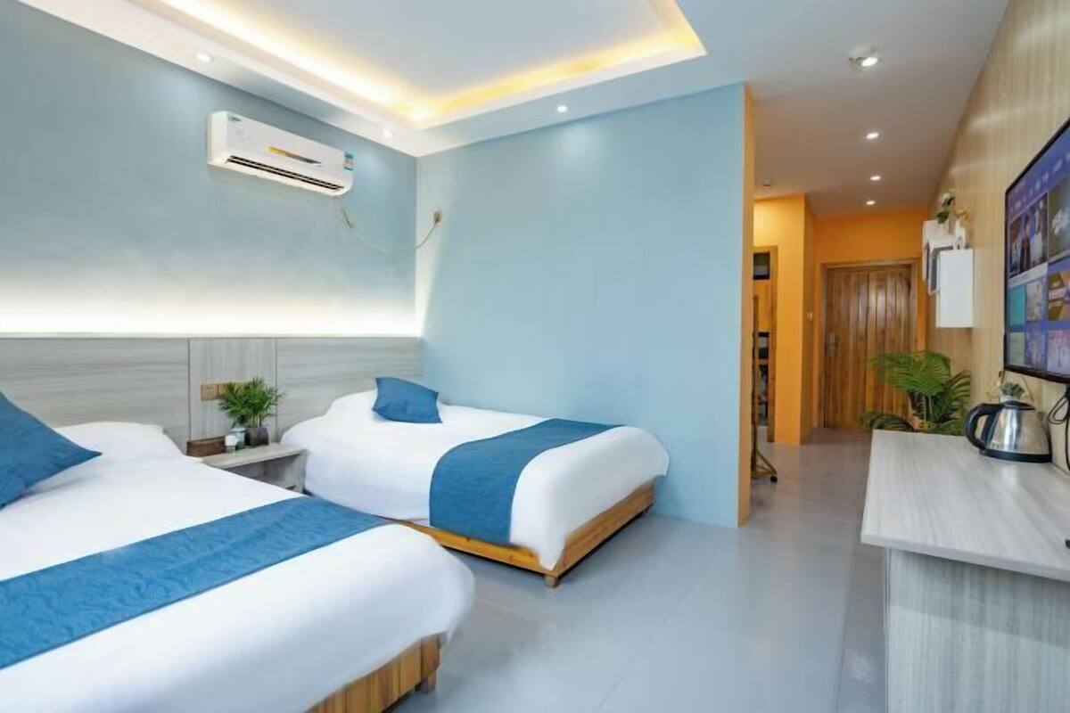 Ein Hotelzimmer mit zwei Betten, einem Schreibtisch und einer Klimaanlage.