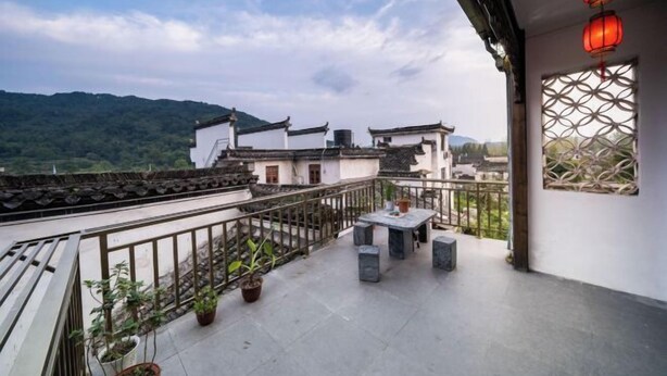 Un balcon avec une table et des chaises, des plantes en pot et des lanternes traditionnelles.