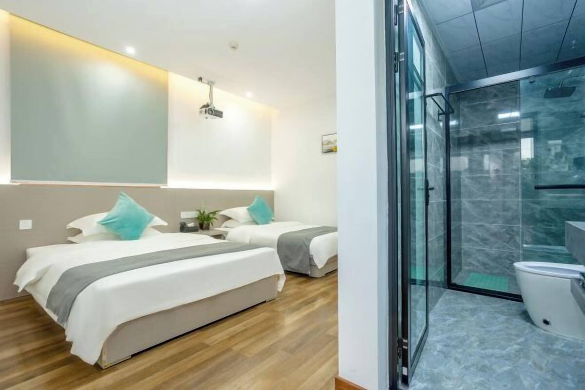 Ein modernes Hotelzimmer mit einem großen Bett, einer Duschkabine und einer Glasabtrennung.