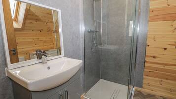 Un baño con ducha de vidrio, un lavamanos blanco y un espejo.