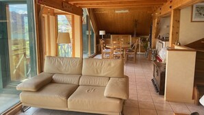 Une pièce chaleureuse avec un canapé, un plafond en bois et un coin repas.