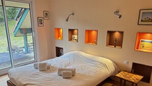 Une chambre à coucher avec un grand lit, des tables de chevet, des lampes fixées au mur et des tableaux encadrés.