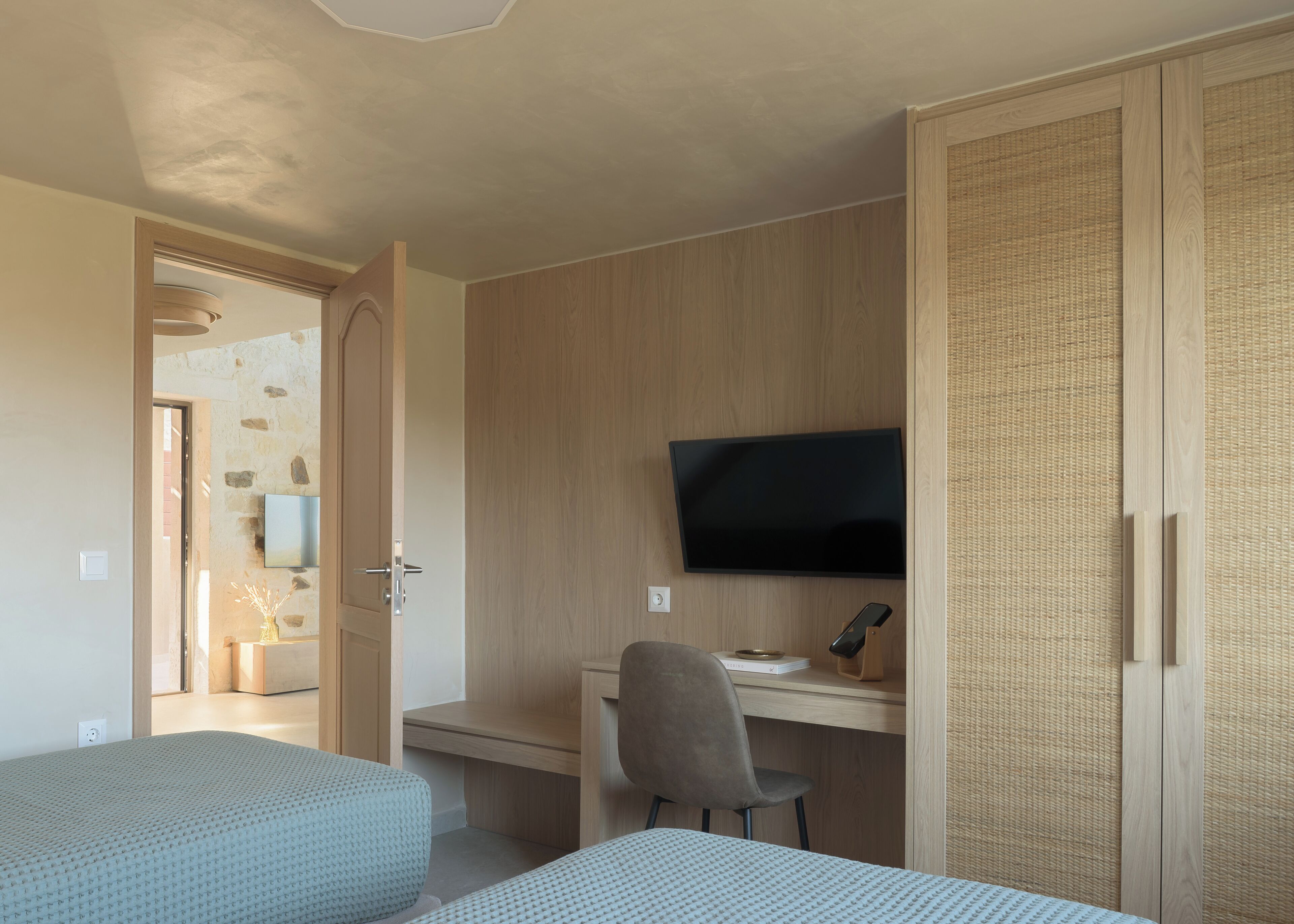 Ein Schlafzimmer mit zwei Betten, einem Schreibtisch mit Stuhl, einem Fernseher und einem Kleiderschrank.